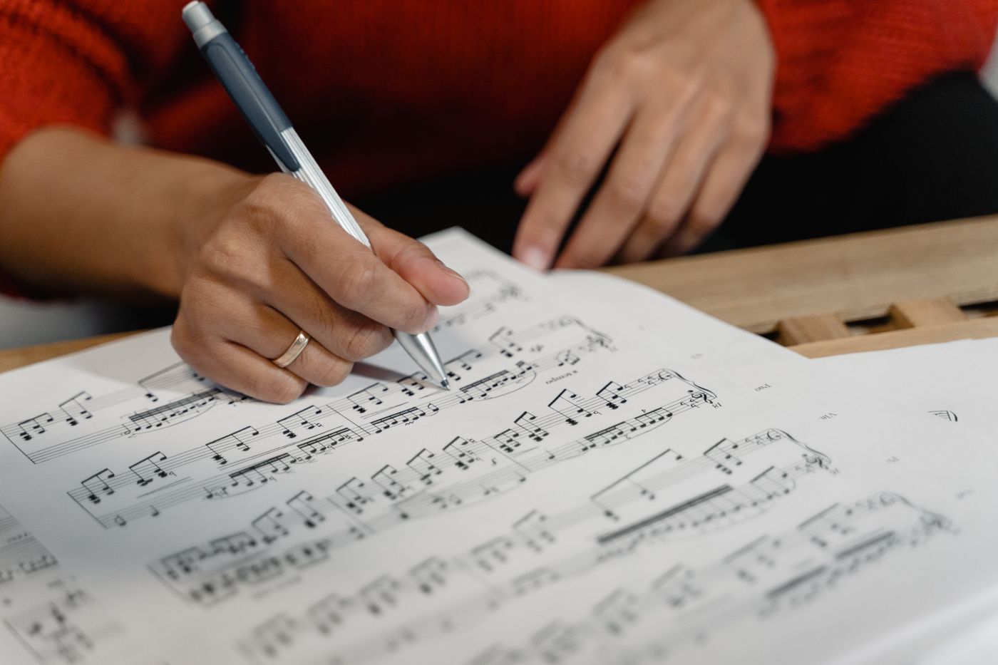 Hands writing notes on a music score with a pen
